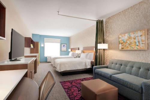 Home2 Suites By Hilton Harrisburg في هاريسبورغ: غرفه فندقيه بسرير واريكه