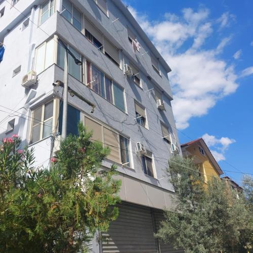 een hoog wit gebouw met bomen ervoor bij 1-8 Lovely quite appartament in Tirana