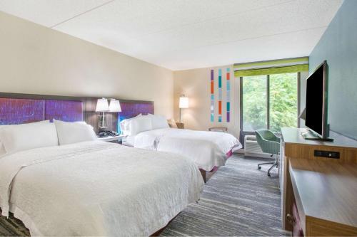 a hotel room with two beds and a flat screen tv at Hampton Inn Fishkill in Fishkill