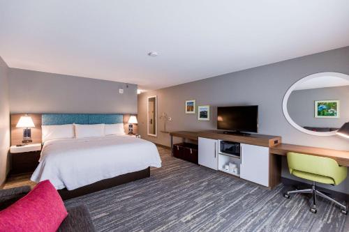 um quarto de hotel com uma cama e uma televisão de ecrã plano em Hampton Inn Bismarck em Bismarck