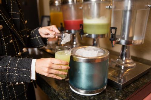 a person is making a drink in a blender at Minas Garden Hotel in Poços de Caldas
