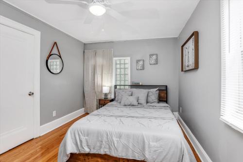 a white bedroom with a bed and a clock on the wall at Modern & Cozy East Side Gem ~ Queen Beds ~ Parking in Detroit