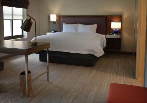 Hampton Inn & Suites Philadelphia/Media في ميديا: غرفة نوم مع سرير كبير مع مكتب وسيدكس سرير