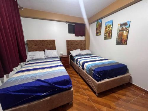 two beds sitting in a room with at Cuzco A 5 min del centro histórico¡Apartamento completo! in Cusco