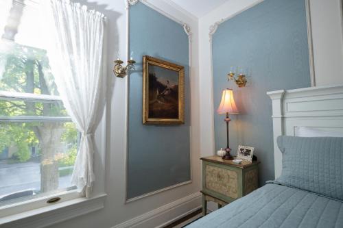 a blue bedroom with a bed and a window at Cartier Mansion in Ludington