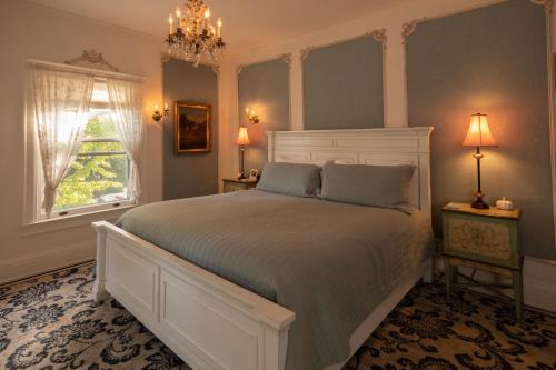 a bedroom with a white bed and a window at Cartier Mansion in Ludington