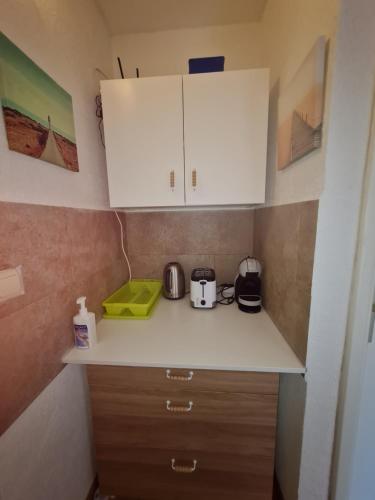 a small kitchen with white cabinets and appliances at Rooms Anđelka in Bol