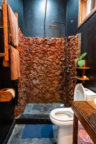 a bathroom with a stone shower with a toilet at La Fontana Zanzibar in Kendwa
