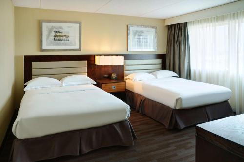 a hotel room with two beds and a window at Hilton Winnipeg Airport Suites in Winnipeg
