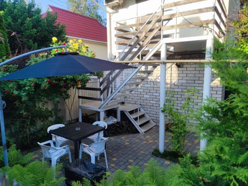 eine Terrasse mit einem Tisch, Stühlen und einer Treppe in der Unterkunft Guest House Odessa Sea in Odessa