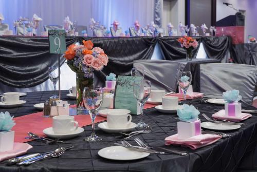 a table with plates and wine glasses and flowers on it at Hilton Winnipeg Airport Suites in Winnipeg