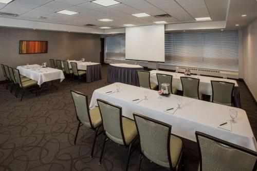 a conference room with tables and chairs and a whiteboard at Hilton Winnipeg Airport Suites in Winnipeg