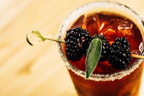 a drink with blackberries on top of it at Hilton Winnipeg Airport Suites in Winnipeg