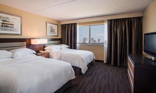 a hotel room with two beds and a flat screen tv at Hilton Winnipeg Airport Suites in Winnipeg