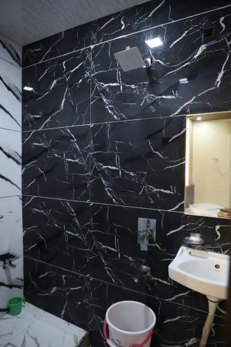 a black marble bathroom with a sink and a mirror at Hotel Mittal Inn in Ajmer