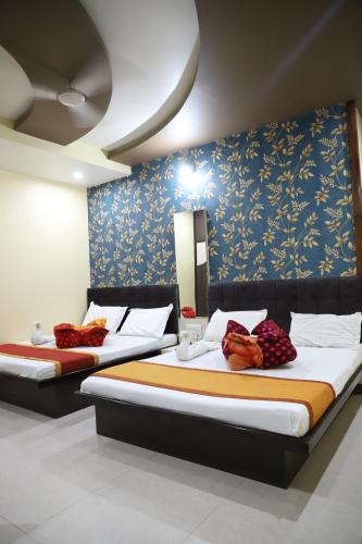 two beds in a room with blue and yellow wallpaper at Hotel Mittal Inn in Ajmer