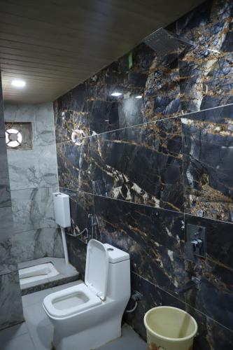 a bathroom with a toilet and a marble wall at Hotel Mittal Inn in Ajmer