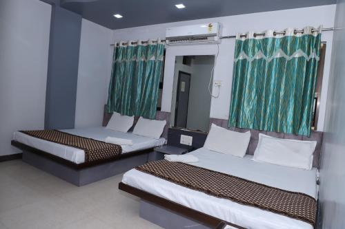 two beds in a room with green curtains at Hotel Mittal Inn in Ajmer
