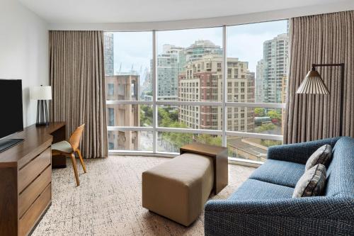 a living room with a blue couch and a large window at Hilton Vancouver Downtown, BC, Canada in Vancouver