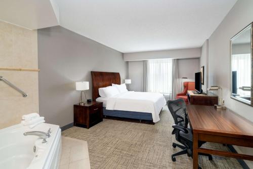 a hotel room with a bed and a desk and a sink at Hilton Garden Inn Augusta in Augusta