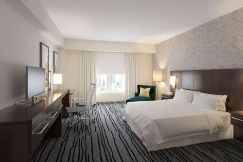 a hotel room with a bed and a desk and a television at The Mosey Buffalo Williamsville Tapestry Collection Hilton in Williamsville