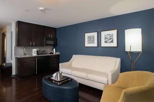 a living room with a white couch and a blue wall at The Mosey Buffalo Williamsville Tapestry Collection Hilton in Williamsville