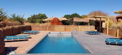 a swimming pool with blue lounge chairs next to at Lodge Altitud in San Pedro de Atacama