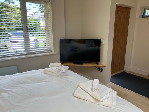 a bedroom with a bed and a tv and towels at Studio 33 in Chichester
