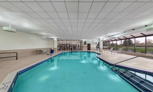 a large swimming pool with blue water in a building at Embassy Suites by Hilton Milwaukee Brookfield in Brookfield