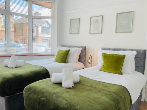 2 camas en una habitación con verde y blanco en Lovely 4 Bed, Family & Contractors Luton Airport & M1 by Properties2you, en Luton