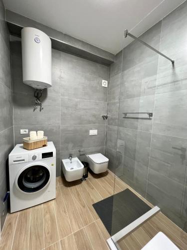 a bathroom with a washing machine and a toilet at George apartments2023 in Korçë