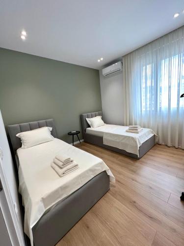 a bedroom with two beds and a window at George apartments2023 in Korçë