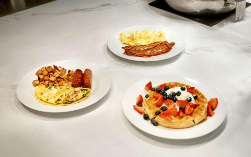 Hilton Garden Inn Salt Lake City/Sandy في ساندي: ثلاثة أطباق من الطعام على طاولة مع طعام الإفطار