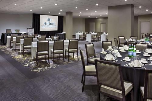 a conference room with tables and chairs and a screen at Hilton Suites Toronto-Markham Conference Centre & Spa in Markham