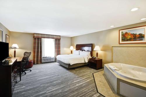 a hotel room with a bed and a bath tub at Hilton Garden Inn Riverhead in Riverhead