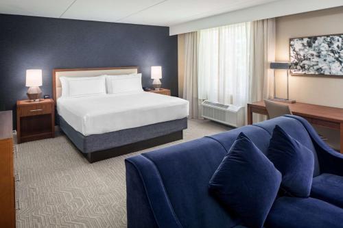 a hotel room with a bed and a blue couch at DoubleTree by Hilton Ann Arbor, MI in Ann Arbor