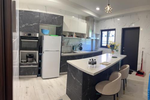 a kitchen with a white refrigerator and a table at 墾丁南灣包棟 光宿宅旅少人也可包棟 in Nanwan