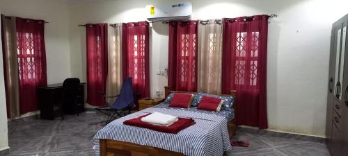 a bedroom with red curtains and a bed with red pillows at OGK, Ghana in Accra