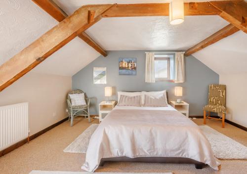 a bedroom with a bed and two chairs in a attic at Dairy Cottage in Swimbridge