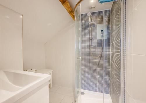 a white bathroom with a shower and a sink at Dairy Cottage in Swimbridge