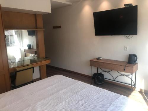 um quarto com uma cama e uma televisão de ecrã plano na parede em Hotel London Palace em Montevidéu