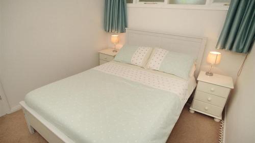 a small bedroom with a white bed and two night stands at 9_304 Redcliffe Apartments, Caswell Bay in Bishopston