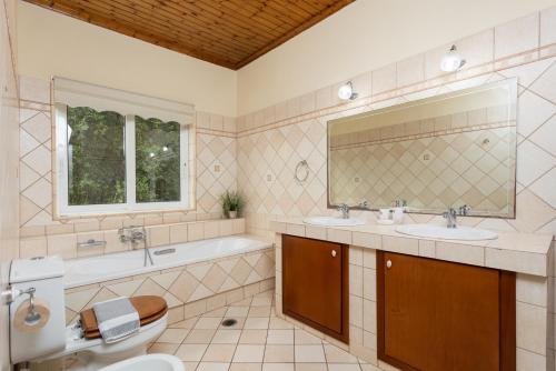 a bathroom with two sinks and a tub and a toilet at Villa Eleni in Agnítsini
