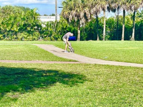 a man bending over on a path in a park at GORGEOUS VIEW Pool, Park, Mall, Beaches, Airport in Plantation