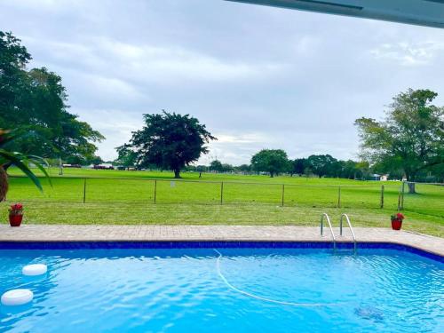 a blue swimming pool with a field in the background at GORGEOUS VIEW Pool, Park, Mall, Beaches, Airport in Plantation