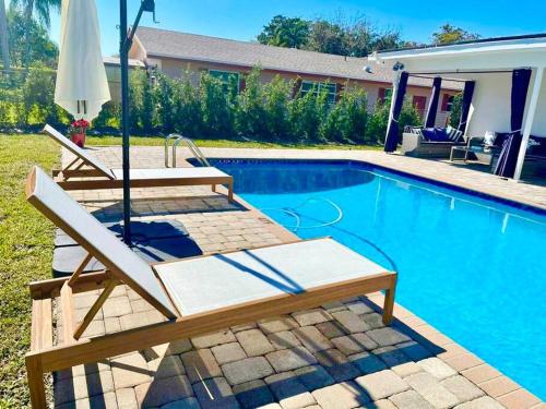 a pool with two lounge chairs and an umbrella at GORGEOUS VIEW Pool, Park, Mall, Beaches, Airport in Plantation
