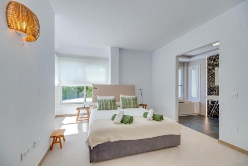 a white bedroom with a large bed with green pillows at VB Higueron 4BDR Villa w Pool, Cinema & Ping pong in Benalmádena