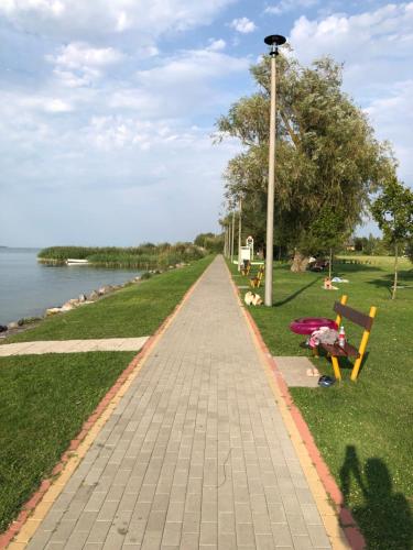 a walkway in a park next to the water at Vadszilva Apartman in Balatonőszöd