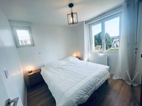 een slaapkamer met een wit bed en een raam bij Au coeur des Chênes, 2p in Ploemeur