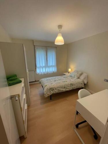 a room with two beds and a table and a desk at Bonito y acogedor apartamento cerca de Donostia San Sebastián in Lezo